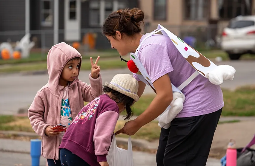 A women's soccer player works with two children in learning soccer.